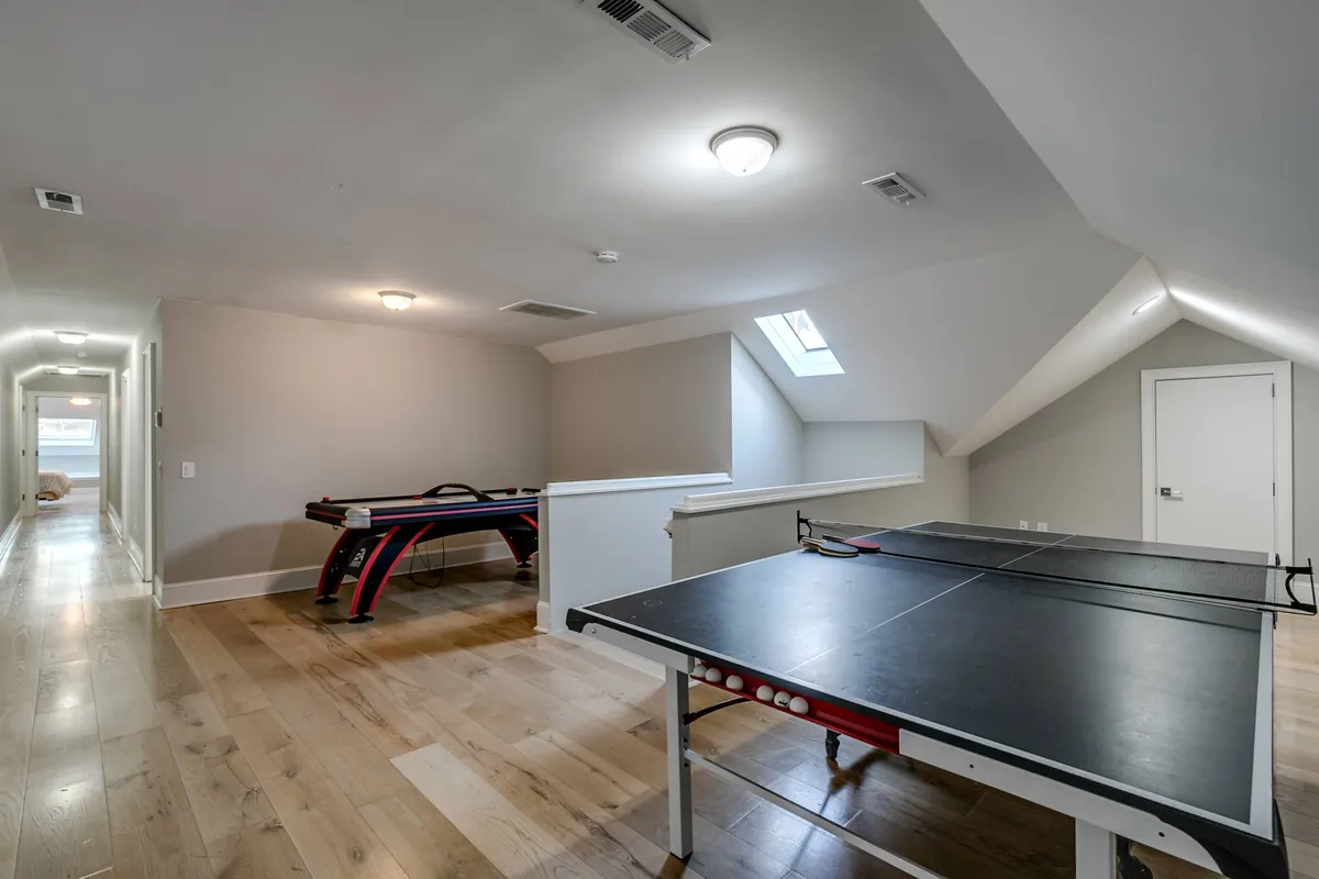 An energetic, well-lit game room featuring a ping pong table, pool table, and a skylight. The space is bustling with opportunities for friendly competition, casual hangouts, and group celebrations—mirroring the fun, communal activities described in the section.