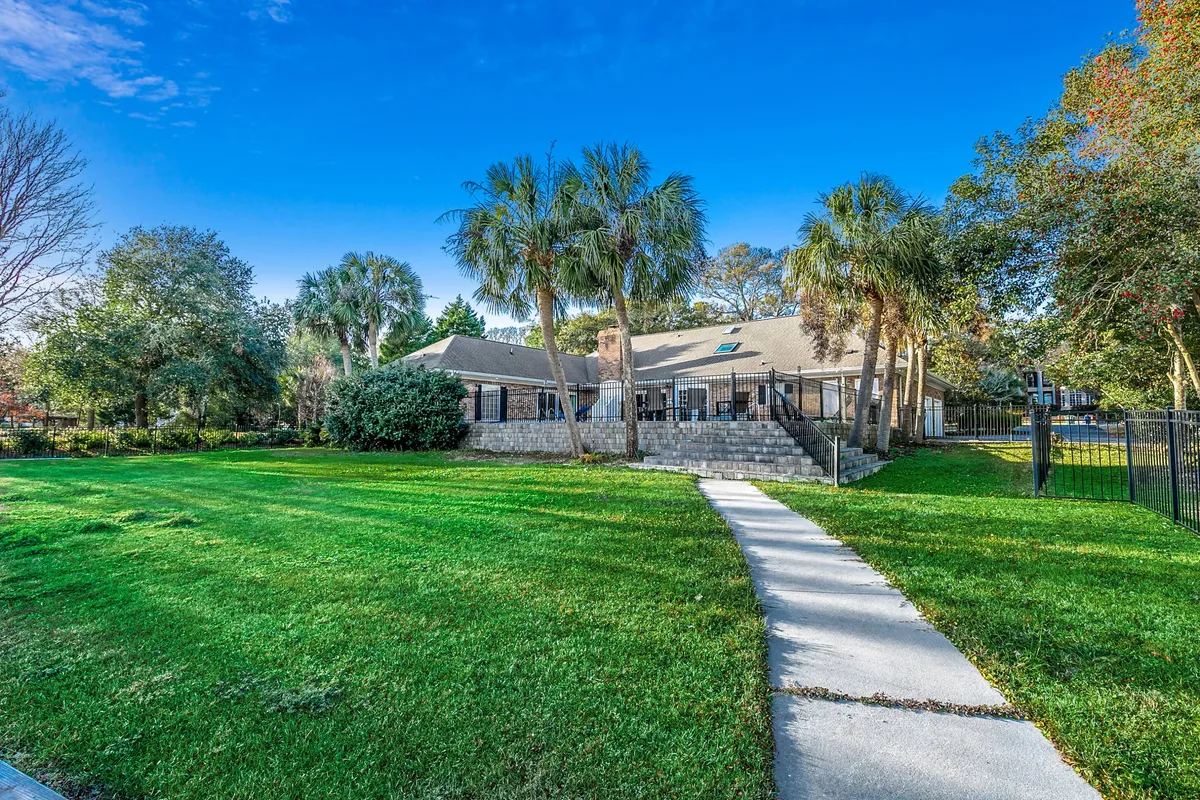 The house is gracefully set within a landscaped yard dotted with palm trees and a welcoming pathway. The space is perfect for gatherings, barbecues, or simply relaxing outdoors. The setting sun casts a warm glow, making the yard feel both peaceful and inviting.