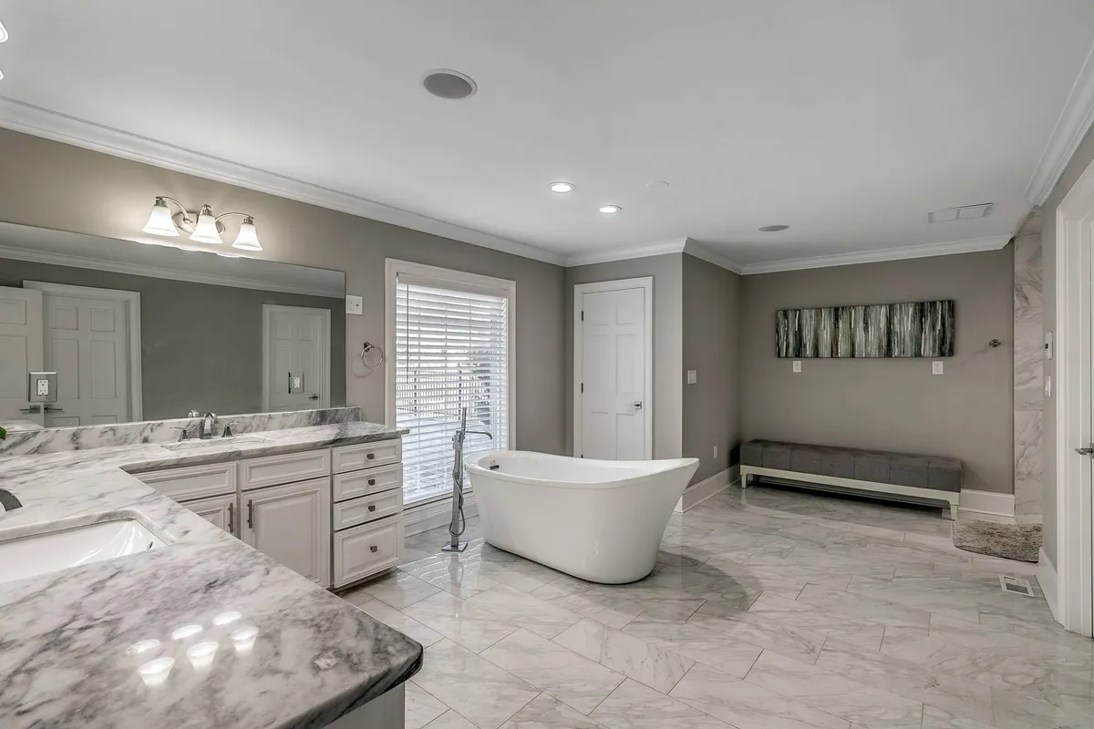 A luxurious bathroom featuring a freestanding bathtub, marble countertop, large mirror, and modern artwork. Soft natural light streams in, creating a spa-like atmosphere perfect for unwinding after a day of adventure.