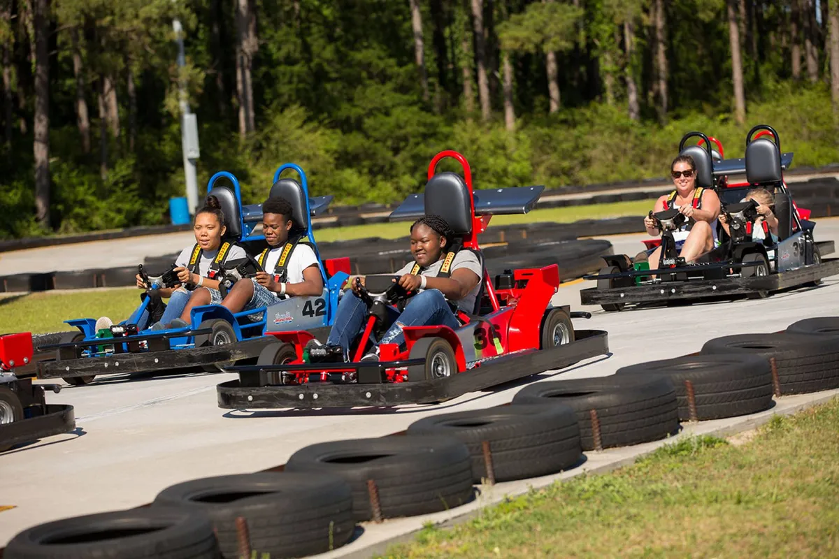 A dynamic view of a go-kart track, featuring racers zipping around the course and spectators cheering them on. The excitement and energy are palpable, highlighting a fun, adrenaline-filled activity perfect for families or groups of all ages.