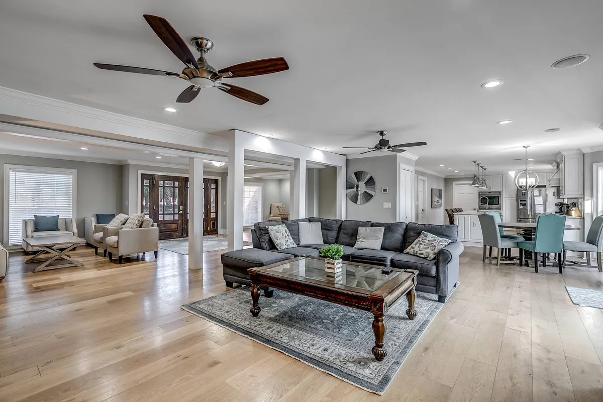 A spacious, open-plan living area with a welcoming seating arrangement, a chic wooden coffee table, decorative rug, and a view into the dining space. The layout suggests both comfort and ample space for gatherings, reflecting upscale interiors with a subtle connection to relaxation after a day of exploring local attractions.
