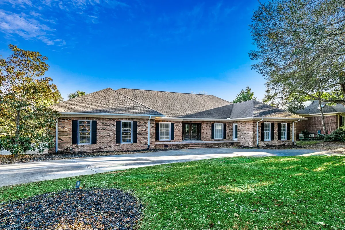 The image showcases the brick exterior of a spacious single-family house with a grand front porch, surrounded by a beautifully landscaped yard. The porch glows with the warm hues of sunset, and the inviting space hints at cozy gatherings and morning coffee moments. Seasonal decorations add a festive touch, enhancing the welcoming atmosphere.