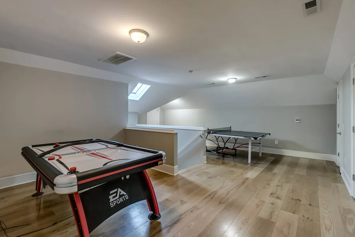 A lively game room with an air hockey table and a ping pong table set in a bright, energetic space. The room is clearly designed for interactive fun and group activities, with ample space for social gatherings or family game nights.